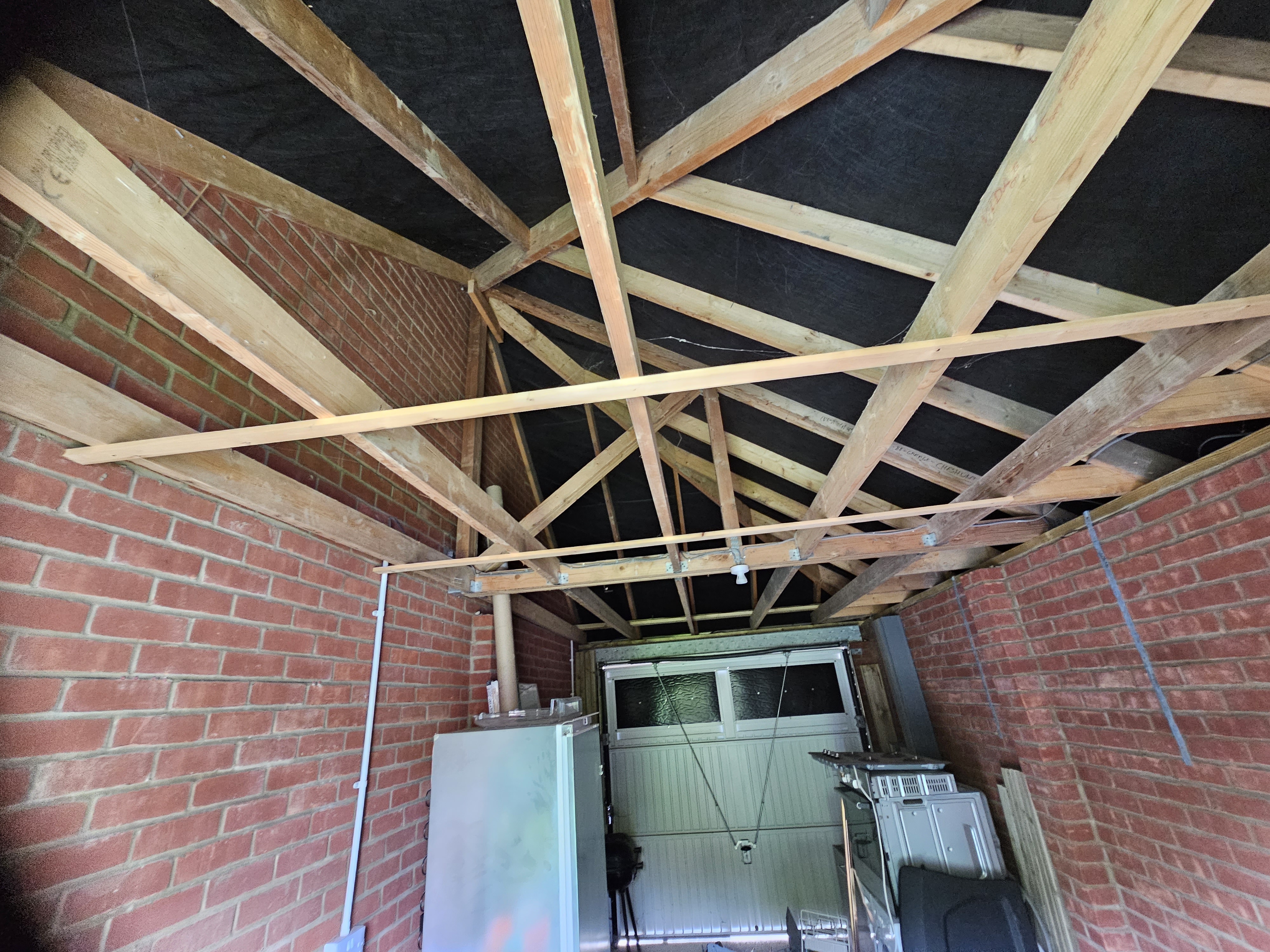 Original garage interior showing exposed trussed roof and brick walls — Huxley Close, before conversion