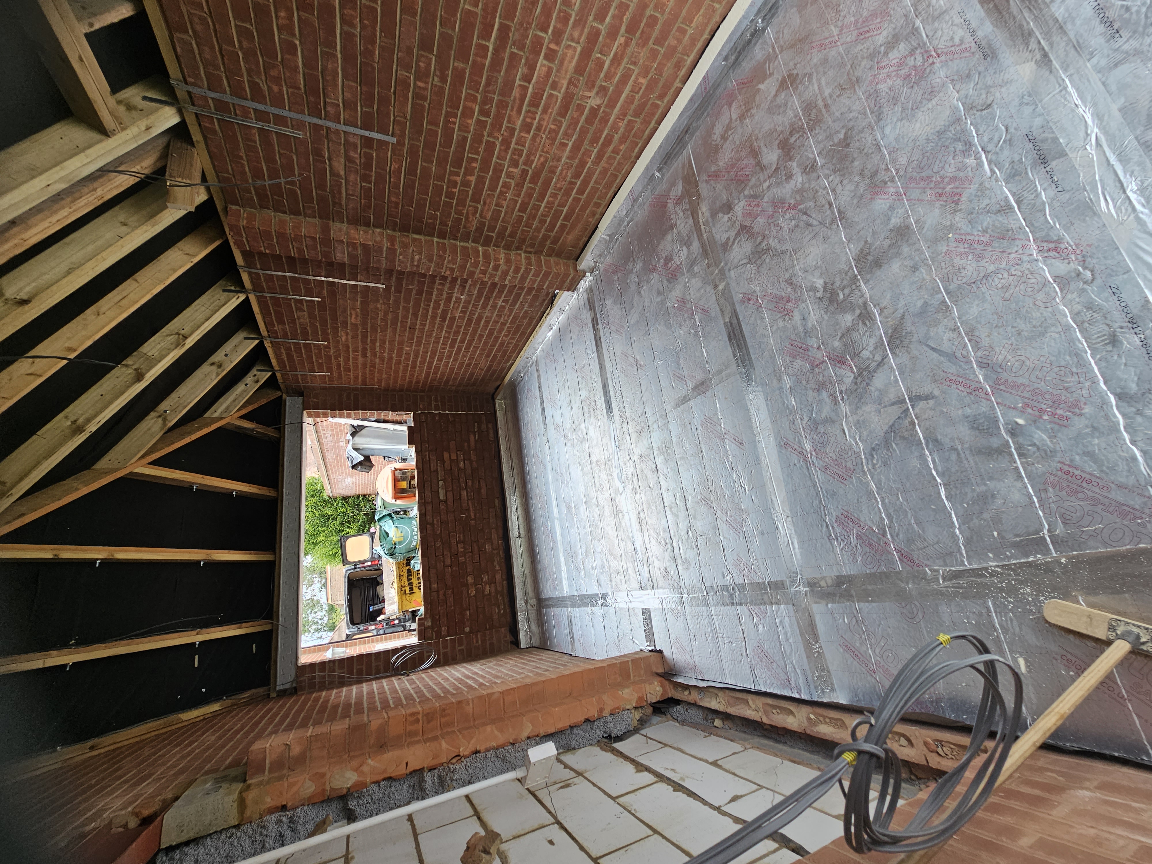 Garage-door opening partly bricked up for a new window with floor insulation laid — Huxley Close during conversion