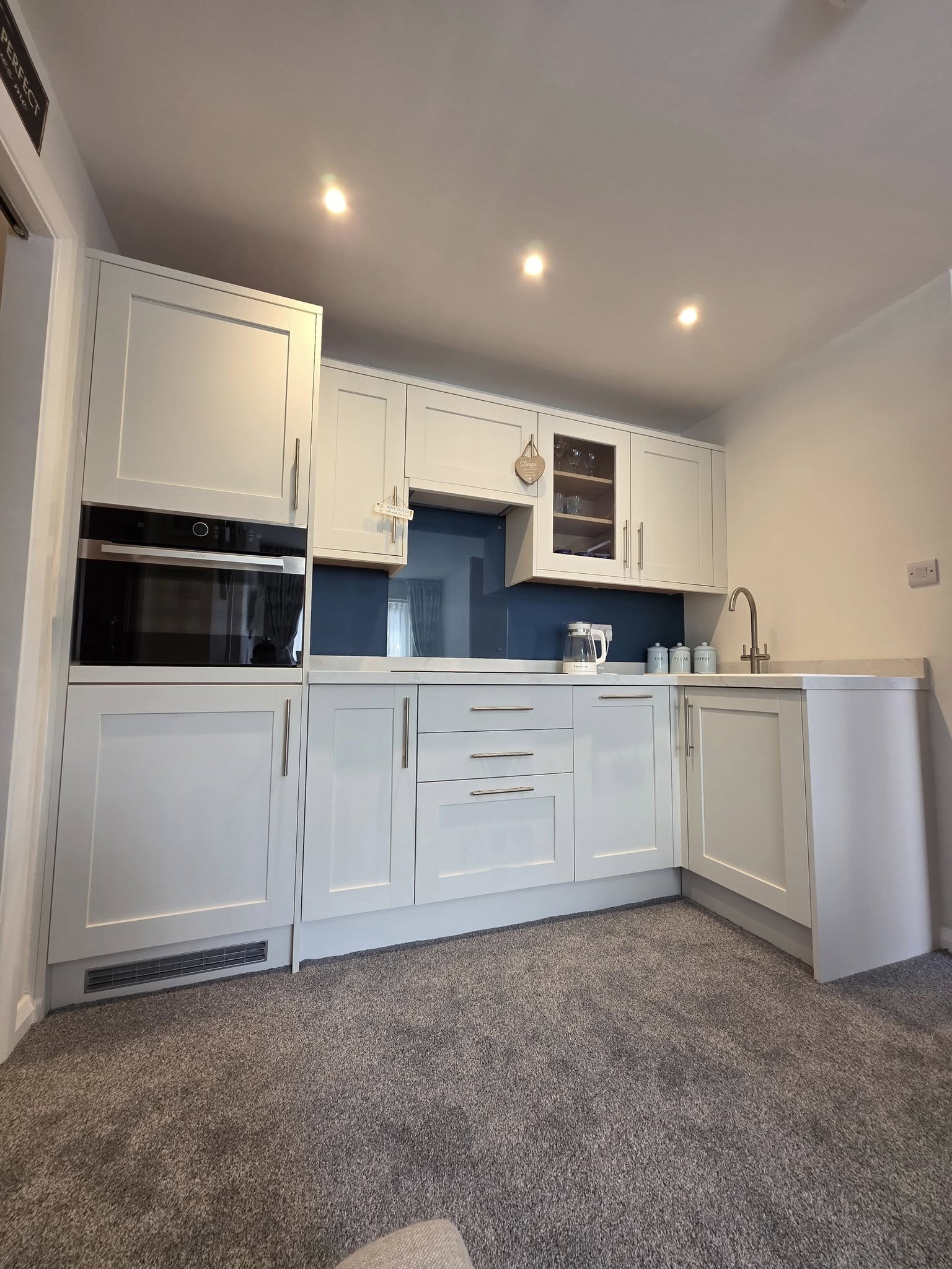 Completed annexe kitchen — white shaker units, blue glass splashback and integrated appliances, Chelmsford