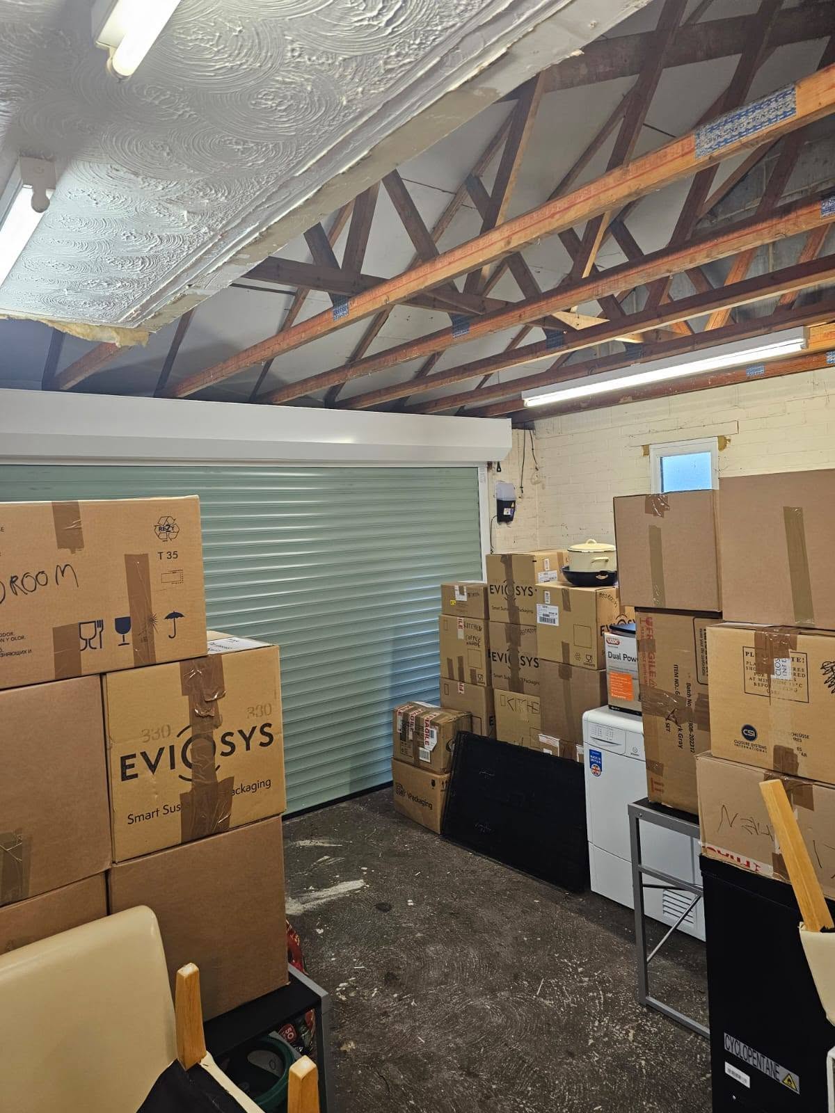 Original double garage before conversion — storage-filled interior with exposed brick walls, Chelmsford