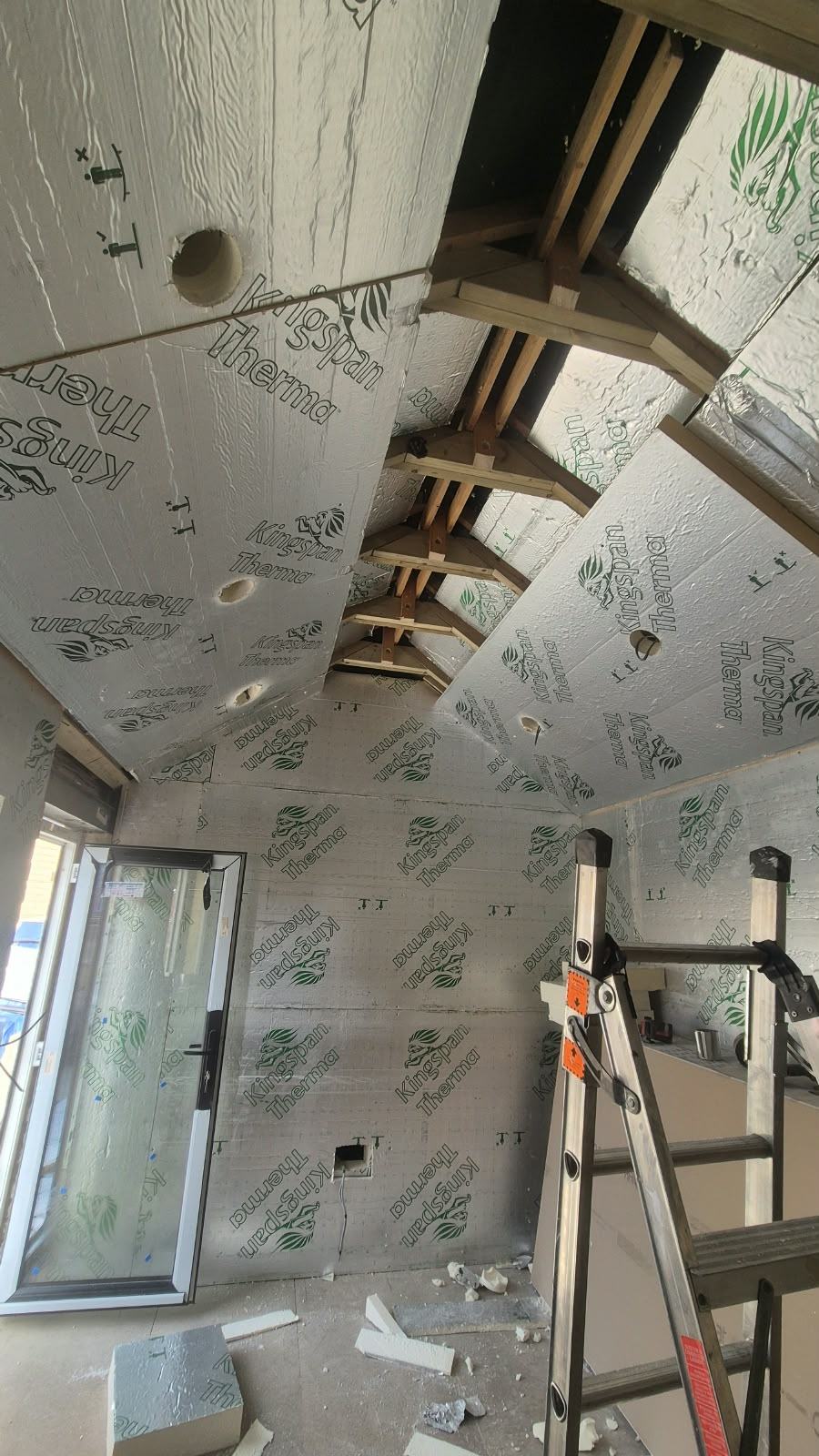 Foil-faced insulation fitted to the sloping office ceiling with openings prepared for recessed lights