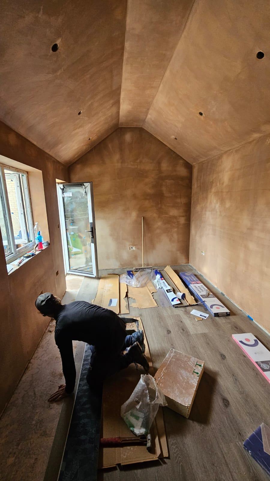 Wood-effect flooring being installed inside the freshly plastered Dunmow garage office