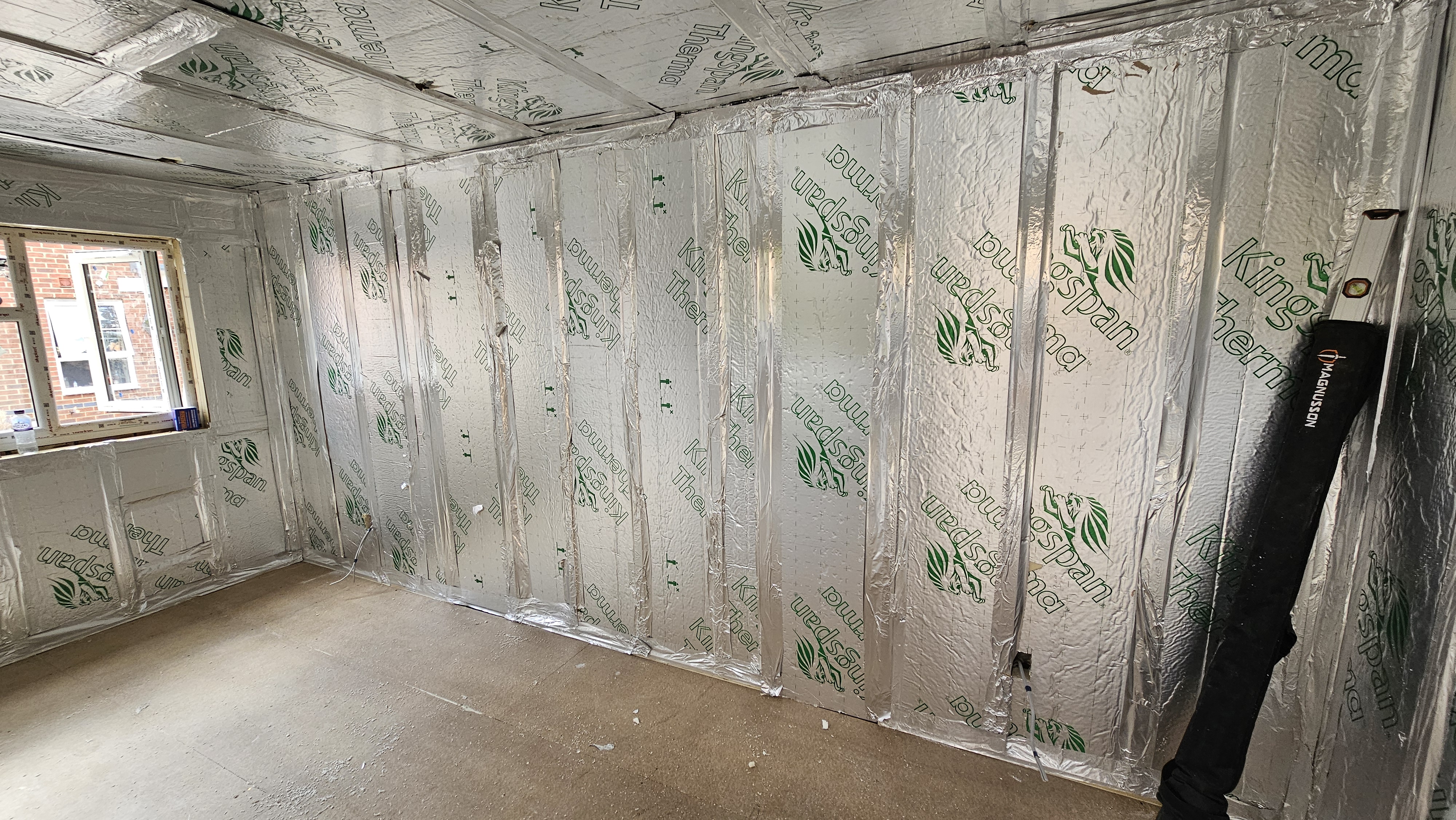 Foil-faced rigid insulation fitted continuously between the timber wall linings