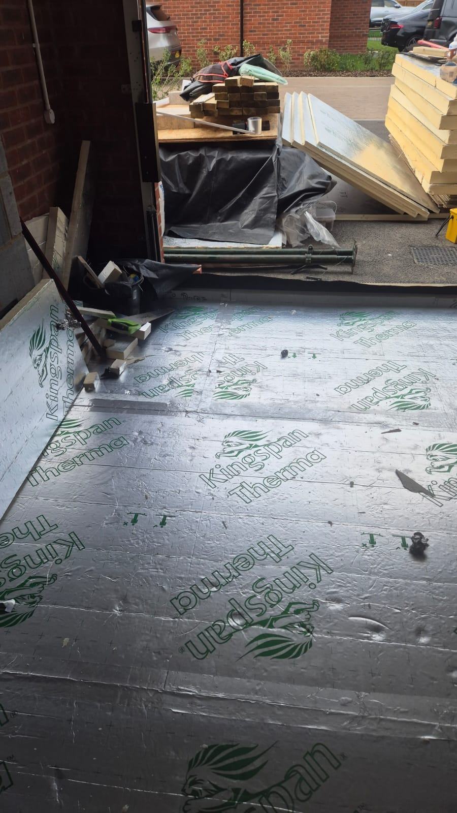 Foil-faced rigid insulation laid across the garage floor towards the original vehicle opening in Waltham Cross